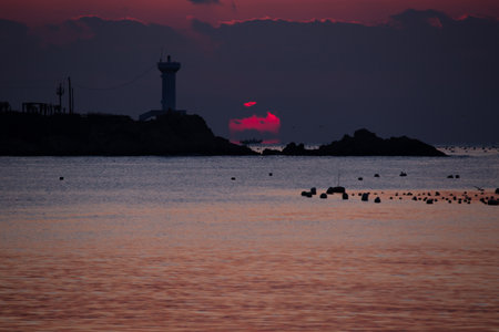 a sea sunrise with a lighthouseの写真素材