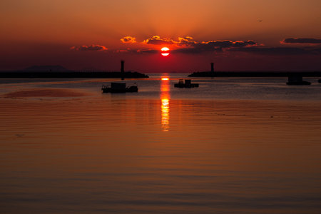 a sea sunrise with a lighthouse and a sun in the cloudsの写真素材