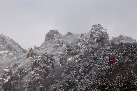 Winter scenery with snow-covered rocky mountains and cable carsの写真素材