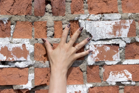 hand pressed against the brick wall women palm fingers manicure ring gold nails red brown whiteの写真素材