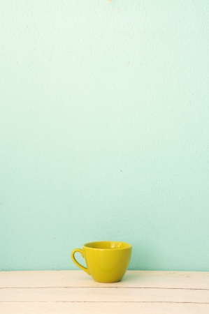 Green coffee cup on the white wood with green grunge wall backgroundの写真素材