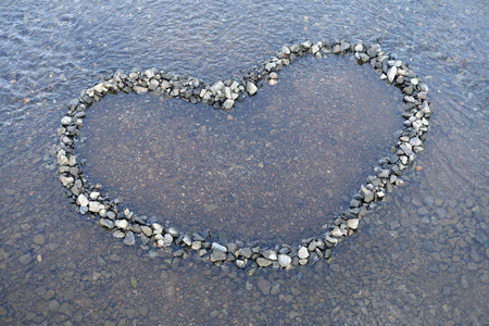 Heart shape made with pebbles on the riverの写真素材