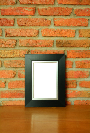 Back picture frame on the old brick wall and the wooden floor backgroundの写真素材