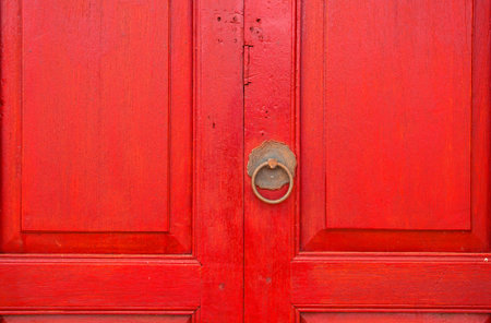 Brass door handle and knocker in chinese style on a red wooden door backgroundの写真素材