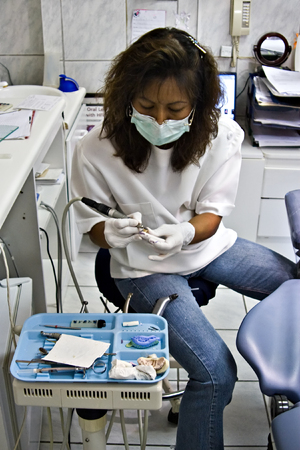 Dentist with rubber gloves polishing one porcelain toothの写真素材
