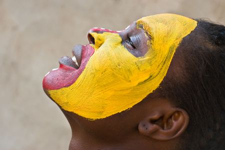 Young African girl, tribal painted face in yellow and red, harmonic triangles use it portrait or landscapeの写真素材