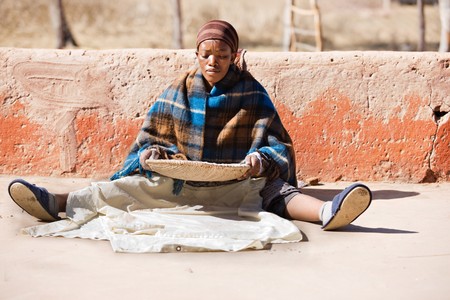 Portrait of African woman with a basket of sorghum, staple food in africaの写真素材