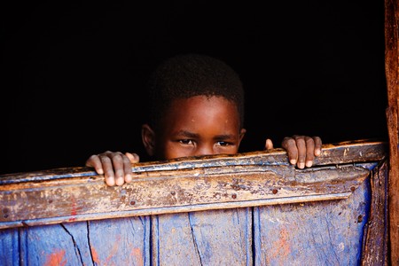 Small African child behind the door of the village house, lomo lookの写真素材