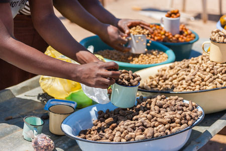 african street vendors selling peanuts, monkey oranges, beans, kumquats oranges