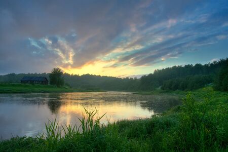 The house on coast of the river, the cloudy sky