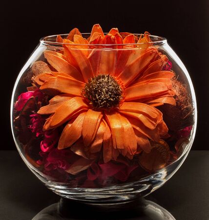 Large pressed flower in a glass vase surrounded by small dry flowersの写真素材