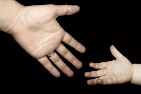 an adult reaching for a child's handの写真素材