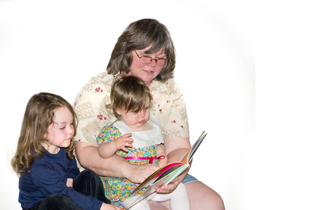 a grandmother reading a story to two little girlsの写真素材