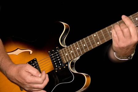 hands planing a guitar on a black background
