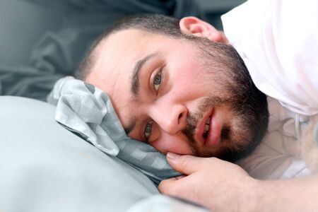 a man laying in bed looking like he is sick
