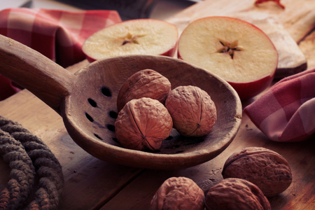 Ancient wooden spoon with walnuts and appleの写真素材