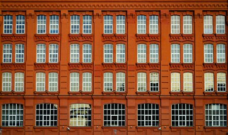 Orange-red architectural facade of the building with large windowsの写真素材
