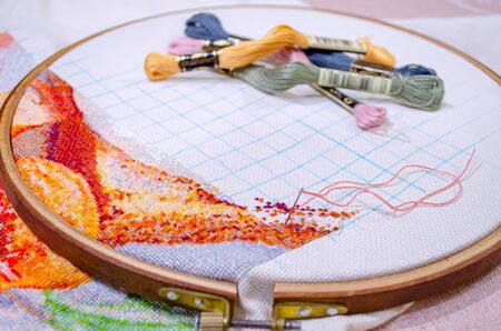 hoops for embroidery with a stretched cloth, sticking out a thread and colored threads on the backgroundの写真素材