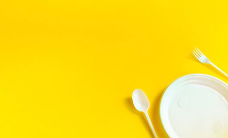 plastic fork, spoon and plate of white on a yellow background