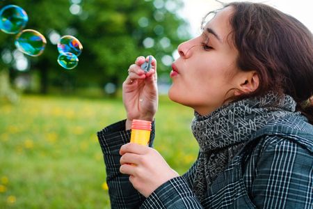 girl blow soap bubble against a background grass