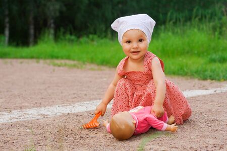 Small pretty girl playing with a doll in the parkの写真素材