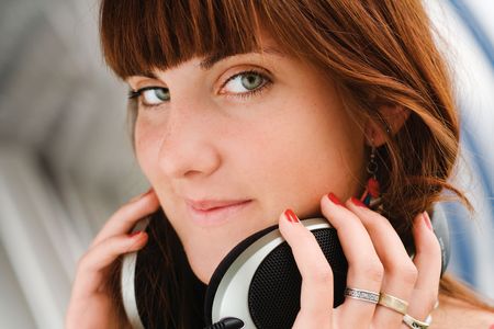 Pretty young girl holding big headphones listening to musicの写真素材
