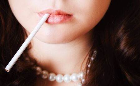 Woman lips holding a thin white cigaretteの写真素材