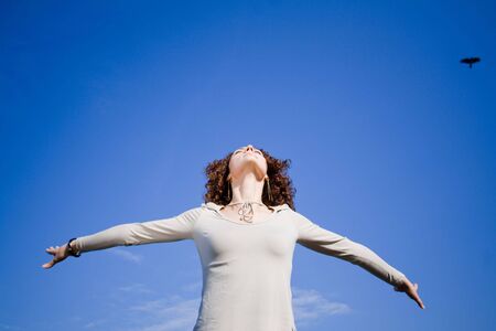 Young woman agains blue sky with arms outstrechedの写真素材