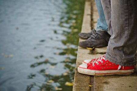 Legs in jeans and sneakers standing by waterの写真素材