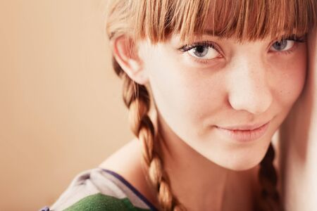 Young smiling girl with a tress by the wallの写真素材