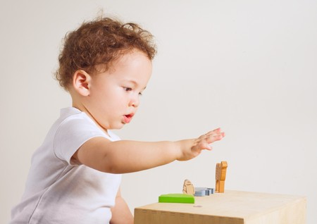Small boy playing with colorful toys on white background