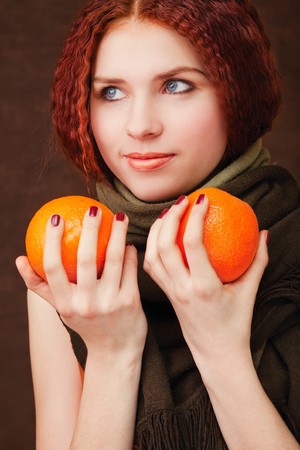 Young pretty girl with two oranges on dark backgroundの写真素材