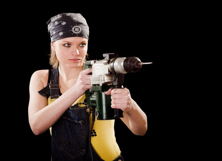 Severe young woman with a drill on black backgroundの写真素材