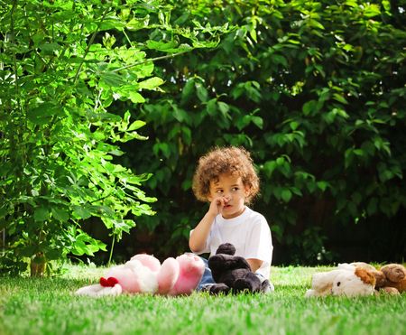 Young boy sitting with toys on grassの写真素材