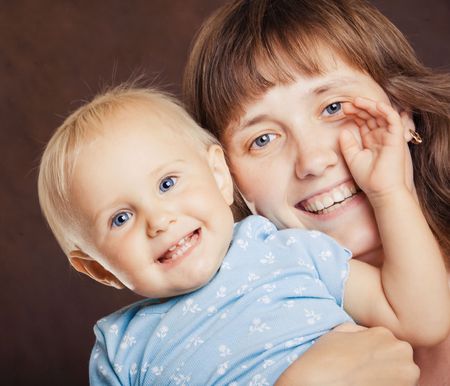 Mother holding small blond baby with blue eyesの写真素材