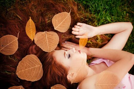 Young pretty girl with red hair lying on grassの写真素材