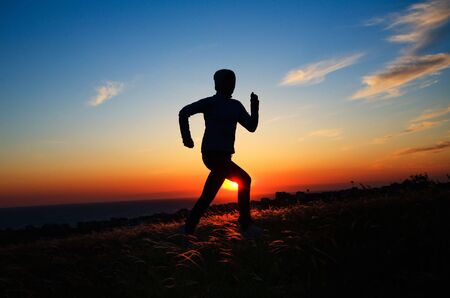 Human silhouette running against sunset skyの写真素材