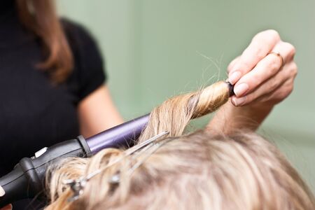 Hairdresser to curl the hair in a beauty salonの写真素材
