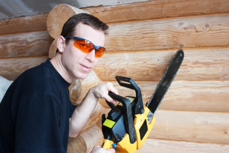 Worker with chainsaw in wooden houseの写真素材