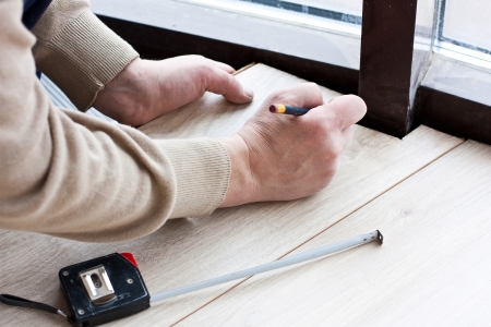 worker makes markup before laying laminate flooringの写真素材
