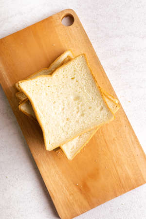 Stack of sliced white bread on cutting board. White background texture. Flat lay.
