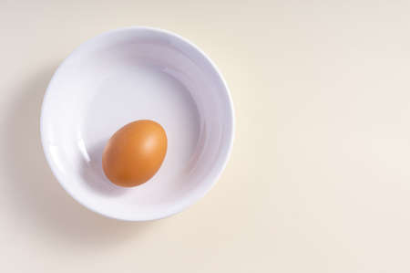 Whole raw egg in white bowl. Top view. Broken White Background.の写真素材