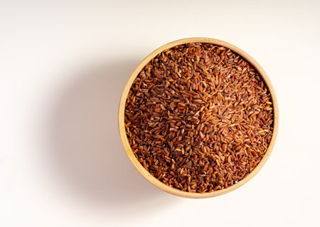 raw red rice in the wooden bowl, isolated on white backgroundの写真素材