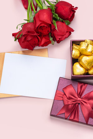 Gifts and red roses on a pink background with blank white card. Valentine's concept. Copy space.の写真素材