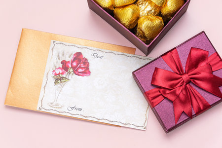Gifts and red roses on a pink background with blank greeting card. Valentine's concept. Copy space.の写真素材