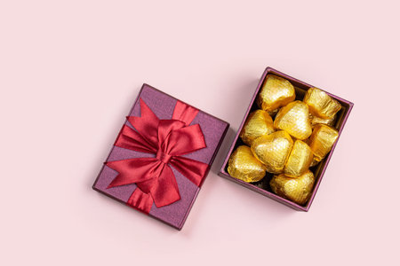 Variety of gifts and chocolates in the shape of a golden heart isolated pink background. Valentine's concept.の写真素材