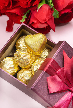 Variety of gifts and chocolates in the shape of a golden heart isolated pink background. Valentine's concept.の写真素材