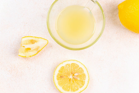A cup of squeezed lemon juice and lemons, slices of lemons around. Bright background. Summer conceptの写真素材