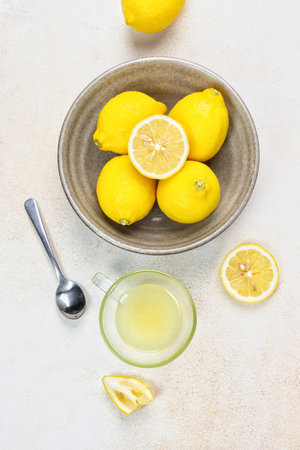 A cup of squeezed lemon juice and lemons, slices of lemons around. Bright background. Summer conceptの写真素材