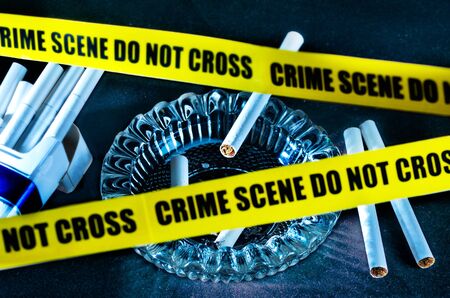 Ashtray and cigarettes with crime scene tape, a warning for the danger of smokingの写真素材